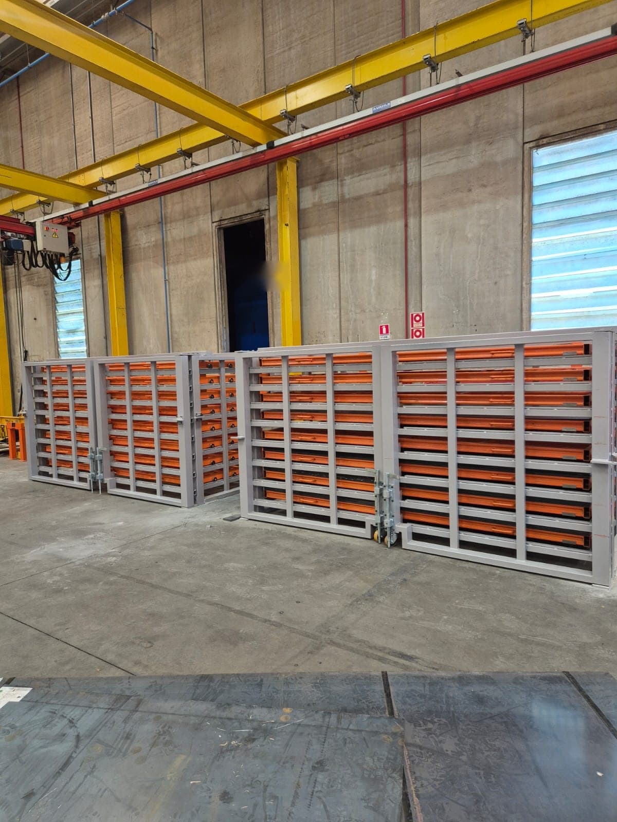 Três racks para chapas instalados em planta industrial, com as gavetas à vista
